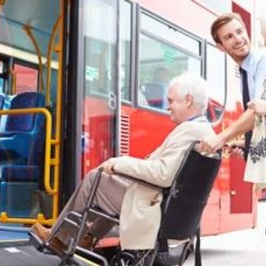 Ältere Dame wird mit dem Rollstuhl in einen Bus gerollt