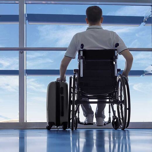 Frau auf elektrischem Rollstuhl fährt durch den Flughafen